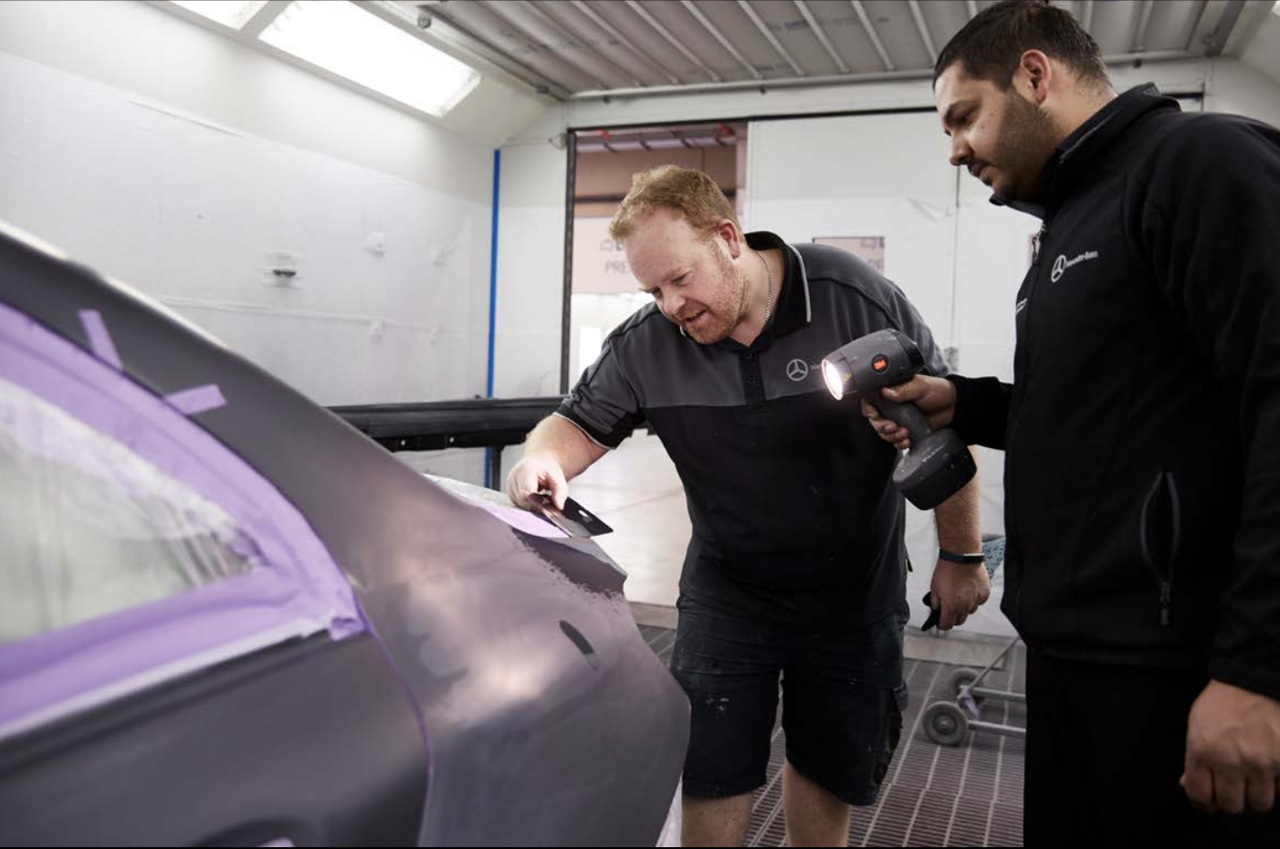 Miranda Auto Body technicians inspecting paint quality in spray booth